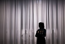 Eine Servicemitarbeiterin steht vor einem hellen Vorhang - Sebastian Gollnow/dpa/dpa-tmn