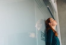 Frau lehnt an Glaswand - Zacharie Scheurer/dpa-tmn