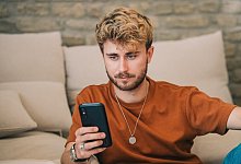 Mann schaut auf ein Smartphone - Zacharie Scheurer/dpa-tmn