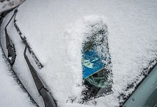 Eine Parkscheibe hinter einer verschneiten Windschutzscheibe - Zacharie Scheurer/dpa-tmn