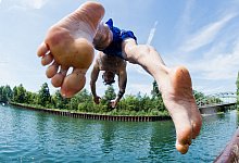 Ein Mann springt ins kühle Nass an einem Kanal - Julian Stratenschulte/dpa/dpa-tmn