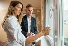 Eine Frau prüft mit einer Flamme die Dichtigkeit eines Fensters - Christin Klose/dpa-tmn