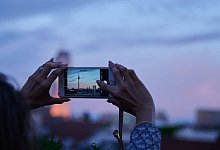 Frau fotografiert mit dem Smartphone den Abendhimmel über Berlin - Annette Riedl/dpa/dpa-tmn