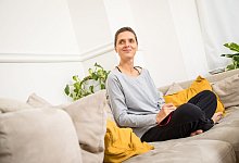 Eine Frau sitzt auf einem Sofa - Christin Klose/dpa-tmn