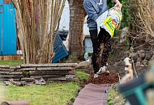 Mann verteilt verteilt Rindenmulch in seinem Kleingarten - Philipp Schulze/dpa/dpa-tmn