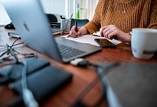 Eine Frau sitzt am Schreibtisch und schreibt eine Bewerbung - Fabian Strauch/dpa/dpa-tmn