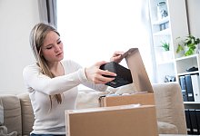 Eine Frau öffnet ein Paket - Christin Klose/dpa-tmn