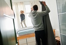 Mann bezieht ein Bett während ein Kind auf dem Bett hüpft - Annette Riedl/dpa/dpa-tmn