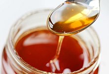 Honig fließt von einem Löffel zurück ins Honigglas - Oliver Berg/dpa