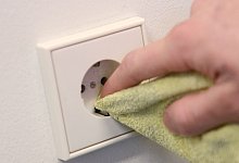 Mann reinigt eine Steckdose - Caroline Seidel/dpa-tmn