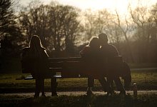 Drei Personen sitzen auf einer Parkbank - Tobias Hase/dpa/dpa-tmn