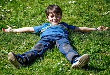 Eine Junge liegt im Gras - Kirsten Neumann/dpa-tmn