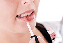 Frau trägt Lipgloss auf - Christin Klose/dpa-tmn