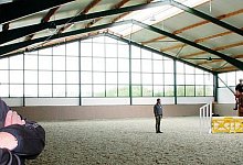 &Uuml;ben in der neuen Halle: Unternehmer Klaus R&ouml;pke beobachtet Betriebsleiter und Springreiter Henrik Griese beim Training mit Maik Schlingheider auf dem Pferd "Caprys". - Foto: Seda Hagemann