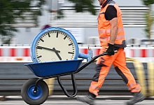 Ein Arbeiter transportiert eine Bahnhofsuhr auf einer Schubkarre - Arne Dedert/dpa/dpa-tmn