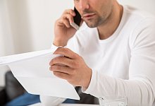 Ein Mann telefoniert und hält einen Brief in der Hand - Christin Klose/dpa-tmn