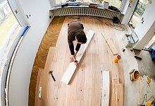 Mann verlegt Echtholz-Parkett in einem Haus - Markus Scholz/dpa-tmn