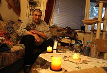 Thorsten Albutat (55) sitzt mit seiner Katze "Hasi" in der Wohnung in Sennestadt. Er friert. In diesem Moment zeigt das Thermometer eine Temperatur von 12 Grad Celsius an. - Ingo Kalischek
