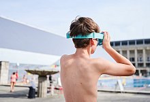 Ein Kind setzt sich seine Schwimmbrille auf - Annette Riedl/dpa/dpa-tmn