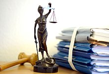 Unterlagen liegen neben einer Nachbildung der Justitia - Volker Hartmann/dpa/dpa-tmn