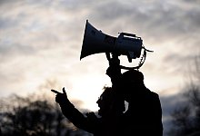 Ein Mann hält ein Megafon bei einem Protest - Marijan Murat/dpa/dpa-tmn