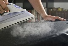 Ein Mann b&uuml;gelt mit einem Dampfb&uuml;geleisen - Franziska Gabbert/dpa-tmn