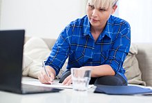 Frau macht sich neben einem Laptop Notizen - Christin Klose/dpa-tmn