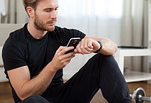 Ein Mann mit Handy und Smartwatch - Christin Klose/dpa-tmn