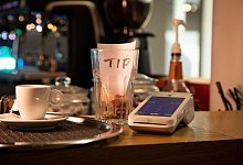 Tresen mit Trinkgeldbecher und Kartenlesegerät an einer Kaffeebar - Christin Klose/dpa-tmn