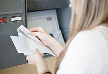 Eine Frau holt Post aus dem Briefkasten - Christin Klose/dpa-tmn