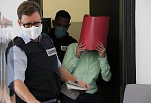 Die Angeklagte verdeckt ihr Gesicht mit einem roten Aktendeckel. - Holger Kosbab