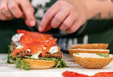 Eine Köchin belegt einen Burger mit veganem Fischersatz - Daniel Karmann/dpa/dpa-tmn