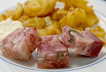 Sülze liegt auf einem Teller mit Bratkartoffeln - Bernd Settnik/dpa/dpa-tmn