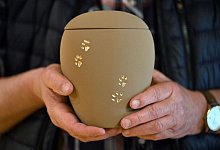 Mann h&auml;lt Urne f&uuml;r Tier-Asche mit Pfoten-Muster - Martin Schutt/dpa