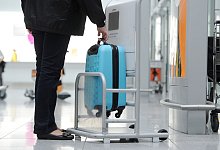 Frau prüft Handgepäckabmessungen - picture alliance / Tobias Hase/dpa-tmn