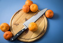 Clementinen liegen neben einem Messer auf einem Holzbrett - Christin Klose/dpa-tmn