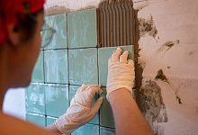 Frau verlegt in ihrer Küche einen Fliesenspiegel - Sebastian Gollnow/dpa/dpa-tmn