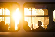 Fahrg&auml;ste sitzen bei Sonnenaufgang in einer Stadtbahn - Julian Stratenschulte/dpa/dpa-tmn