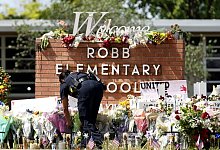 Ein Polizeibeamter legt Blumen vor der Robb Elementary School nieder. - Wu Xiaoling/XinHua/dpa