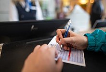 Frau füllt in einem Hotel einen Meldeschein aus - Sebastian Gollnow/dpa/dpa-tmn