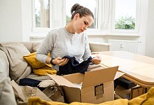 Frau pr&uuml;ft kritisch die Lieferung der online bestellten Ware - Christin Klose/dpa-tmn