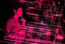 Frau im Neonlicht blickt auf einen digitalen Bildschirm - Uwe Umstätter/Westend61/dpa-tmn