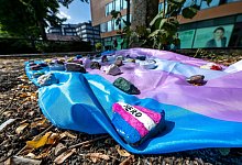 Menschen haben auf dem Hafenplatz eine Fahne ausgelegt, die mit bemalten Steinen beschwert ist. - David Inderlied/dpa/Archivbild