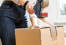 Person klebt Paket mit Klebeband-Abroller zu - Christin Klose/dpa-tmn