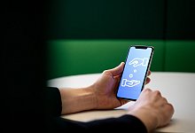 Ein Mann spendet per Smartphone Geld - Zacharie Scheurer/dpa-tmn