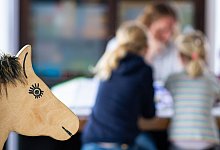 Ein Elternteil sitzt mit seinen Kindern an einem Tisch - Guido Kirchner/dpa/dpa-tmn