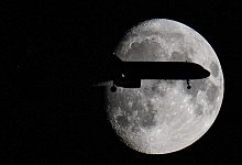 Ein Flugzeug fliegt am Mond vorbei - Boris Roessler/dpa