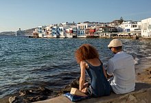 Touristen sitzen auf einer Steinbank - Socrates Baltagiannis/dpa/dpa-tmn
