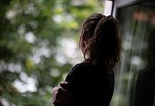 Eine Frau steht am Fenster - Fabian Sommer/dpa/dpa-tmn