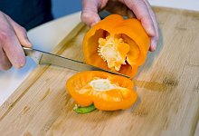 Mann schneidet eine Paprika auf - Karolin Krämer/dpa-tmn